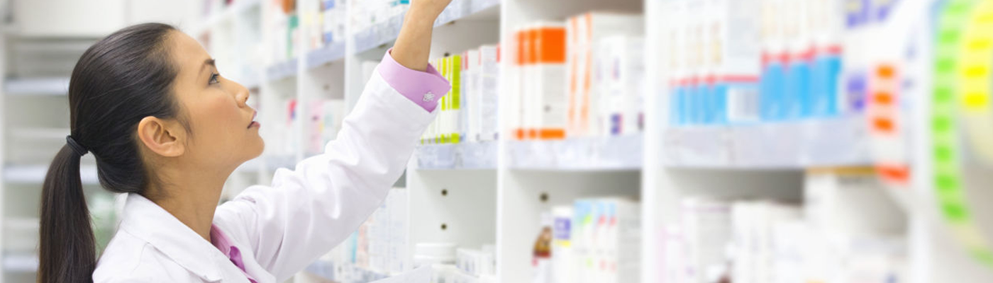 A pharmacy technician, selecting a prescription off the shelf. 