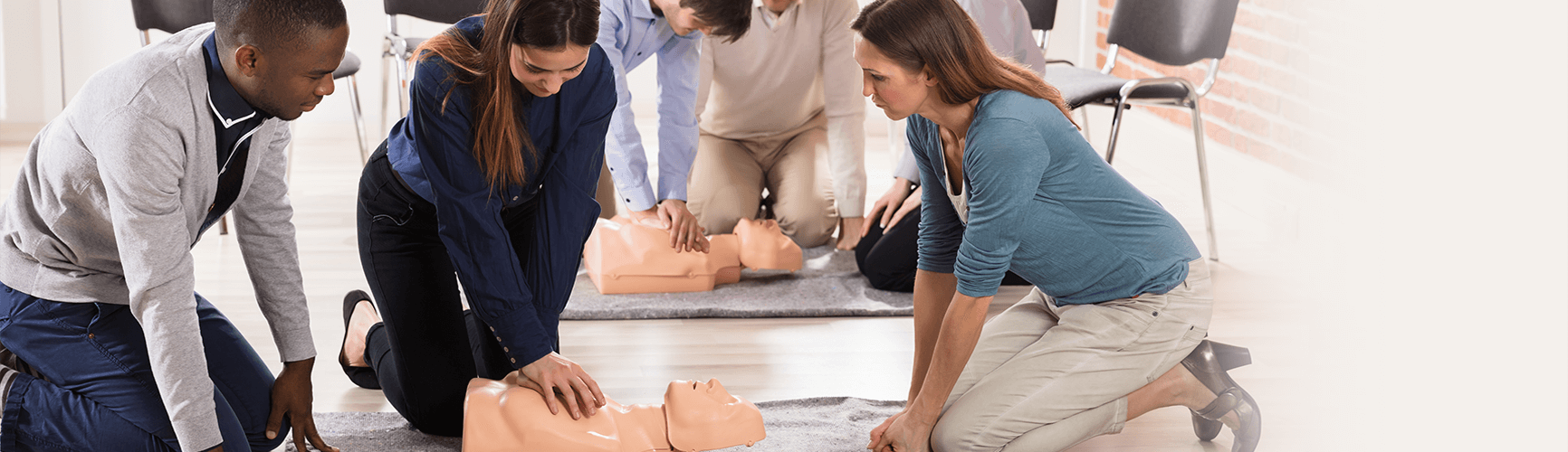 Students participating in AHA classes giving CPR to a dummy. 
